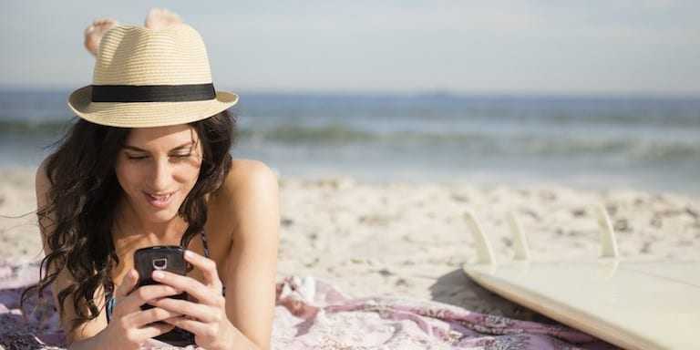USA, New York State, Rockaway Beach, Woman using cell phone on beach
